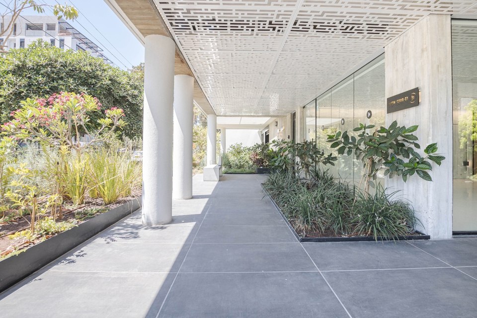 Covered walkway alongside the building, lined with plantings